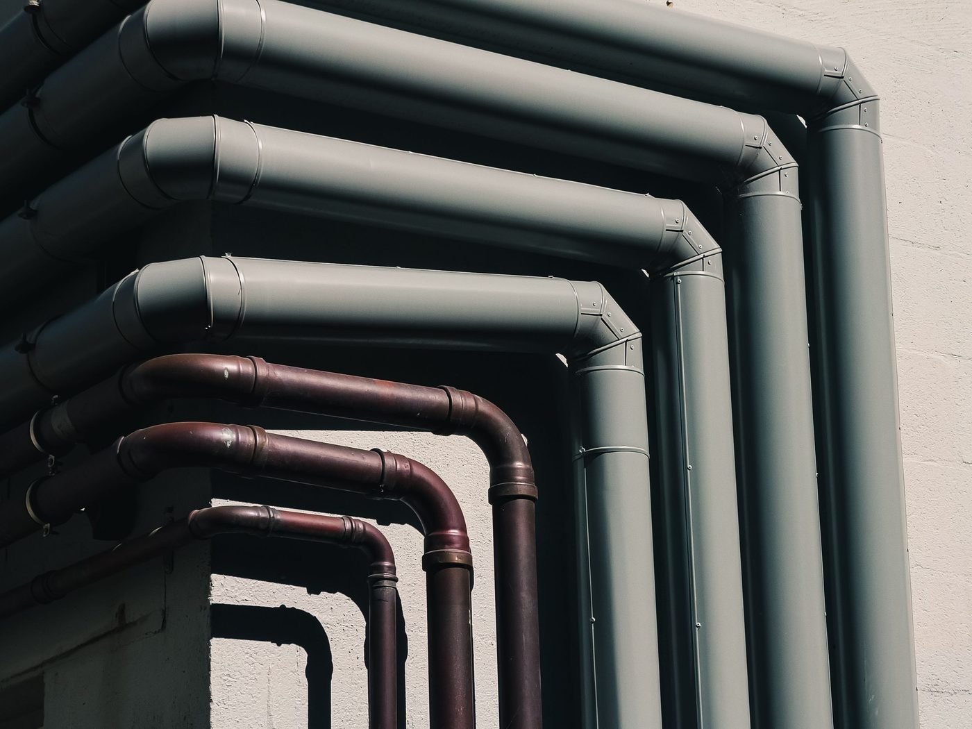 Exterior building downpipes and copper pipe runs against a wall